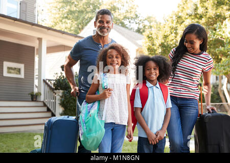 Portrait Of Family With Luggage Leaving House For Vacation Stock Photo