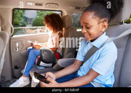 Children Using Digital Devices On Car Journey Stock Photo