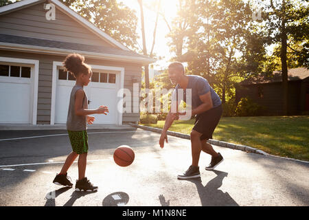 Father And Son Playing Basketball On Driveway At Home Stock Photo