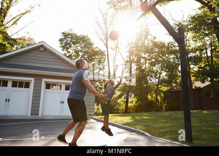 Father And Son Playing Basketball On Driveway At Home Stock Photo