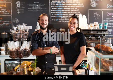 Male And Female Baristas Behind Counter In Coffee Shop Stock Photo