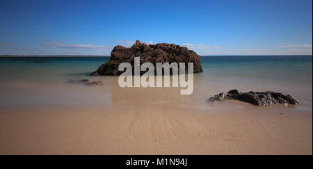 Beach with turquoise sea water with rocks. long exposure. Portugal Stock Photo