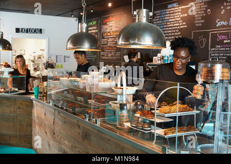 Staff Working Behind Counter In Busy Coffee Shop Stock Photo