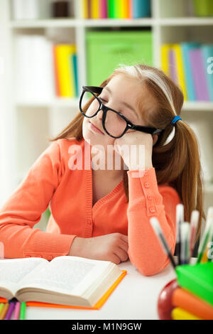 A little  red-haired girl bored with her homework Stock Photo