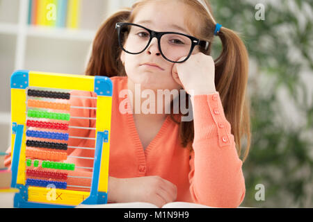 A little  red-haired girl bored with her homework Stock Photo