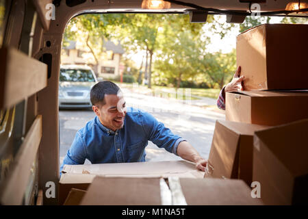 Couple Unloading Boxes From Van On Family Moving In Day Stock Photo