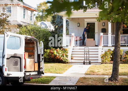 Courier Using Trolley To Deliver Package To House Stock Photo