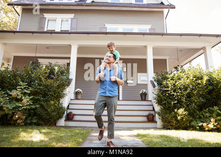 Father Giving Son Ride On Shoulders Outside House Stock Photo