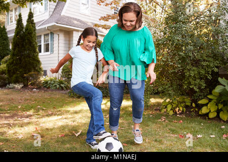 Grandmother Playing Soccer In Garden With Granddaughter Stock Photo