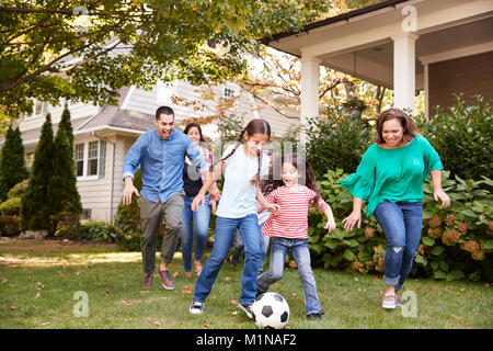 Multi Generation Family Playing Soccer In Garden Stock Photo