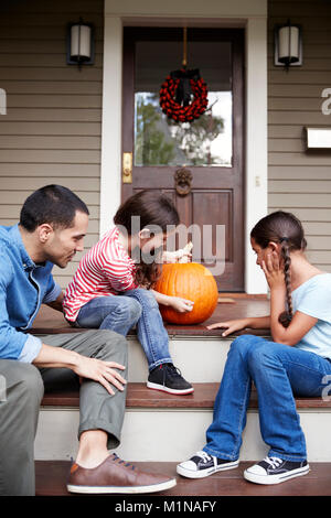 Father And Daughters Drawing Face On Halloween Pumpkin Stock Photo