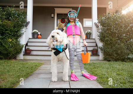 Girl With Dog Wearing Halloween Costumes For Trick Or Treating Stock Photo