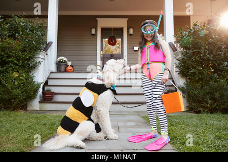 Girl With Dog Wearing Halloween Costumes For Trick Or Treating Stock Photo