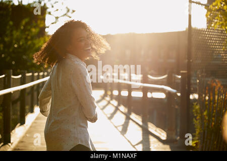 Young Woman Walking Along Bridge In Urban Setting Stock Photo