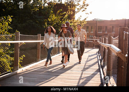 Group Of Friends Walking Along Bridge In Urban Setting Stock Photo