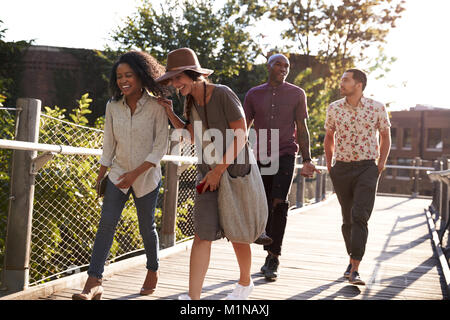 Group Of Friends Walking Along Bridge In Urban Setting Stock Photo