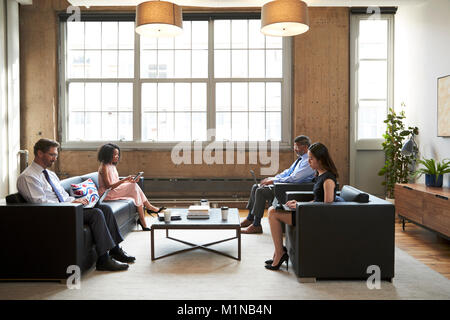 Business people using laptops in a lounge meeting area Stock Photo