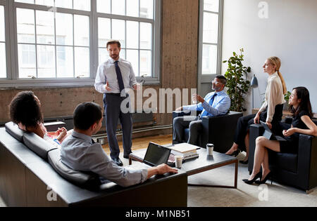 Businessman presenting to colleagues at an informal meeting Stock Photo