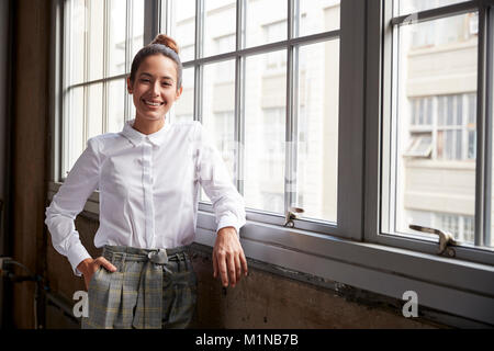 Young white businesswoman with hair bun smiling to camera Stock Photo