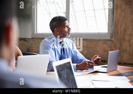 Close up of businessman listening at a boardroom meeting Stock Photo