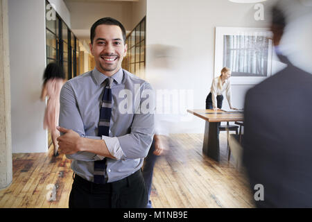 Portrait of young Hispanic man in a busy modern workplace Stock Photo