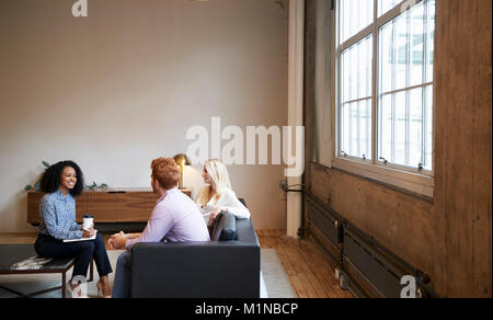 Three colleagues at a casual work meeting in a lounge area Stock Photo