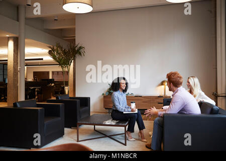 Three colleagues at a casual work meeting in a lounge area Stock Photo