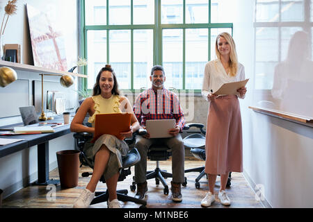 Three coworkers in a team meeting looking to camera Stock Photo
