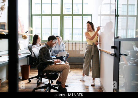 Woman using whiteboard in a small team meeting Stock Photo