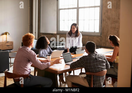 Smiling woman standing to address colleagues at a work meeting Stock Photo