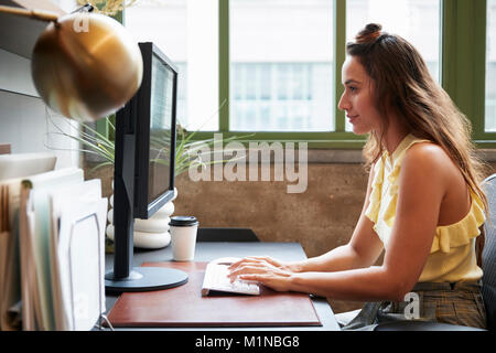 White woman working at a computer in an office, side view Stock Photo