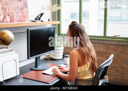 Young white woman using a computer in an office, back view Stock Photo