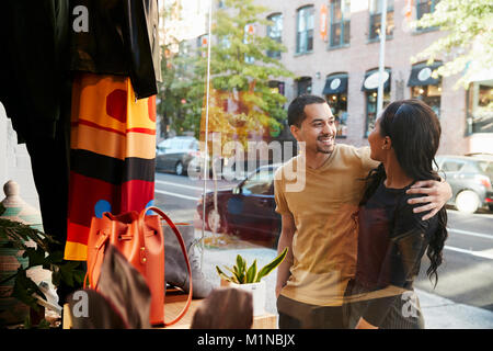 Smiling couple looking at clothes in a shop window Stock Photo