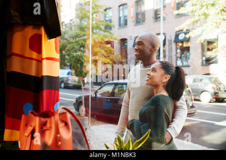 Smiling couple looking in a clothes shop window Stock Photo