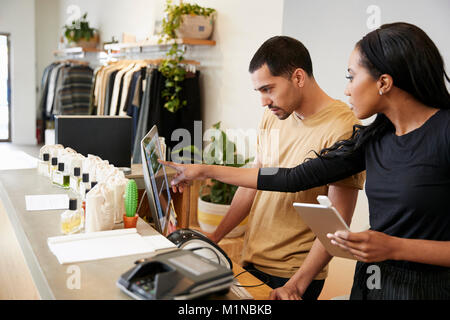 Man and woman working behind the counter in a clothing store Stock Photo