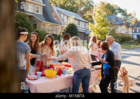 Neighbours talk standing around a table at a block party Stock Photo