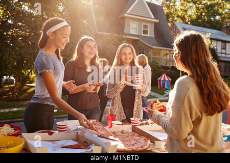 Teen girls eating pizza and talking at a block party Stock Photo