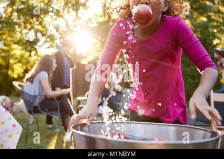 Pre-teen girl apple bobbing, with apple in mouth, close up Stock Photo