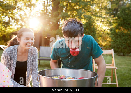 Teenage boy, apple in mouth, apple bobbing at garden party Stock Photo