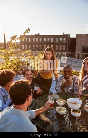 Friends talking at a party on a rooftop, vertical Stock Photo
