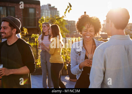 Happy friends at a rooftop party backlit by sunlight Stock Photo
