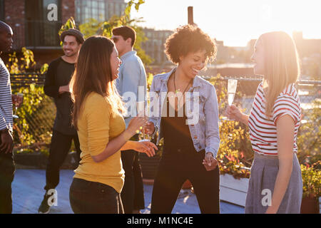 Female friends dancing and drinking at a rooftop party Stock Photo