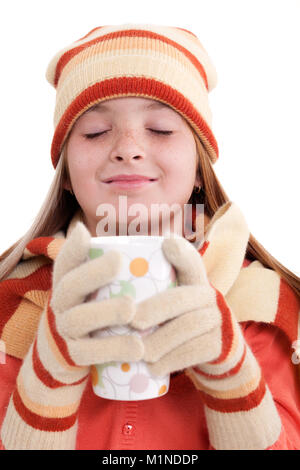 young girl with pigtails in winter clothes holding cup of tea Stock Photo