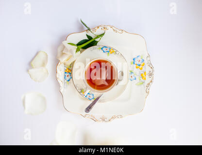 flatlay with elegant tea set with rose flower reflection iat the urface of liquid surrounde by rose petals and flowers Stock Photo