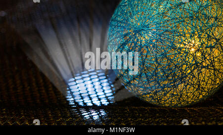 Detail of a sphere covered by net from fibers and mystery light rays in black space. Idea of danger, nuclear weapons, radiation, technology or sci-fi. Stock Photo
