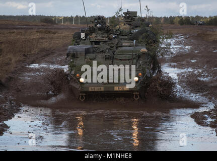 U.S. Soldiers from Kronos Troop, 3rd Squadron, 2nd Cavalry Regiment, drive their Strykers to their battle positions as they participate in a mounted NATO live fire exercise coordinated by the Polish 1st Battalion 15th Mechanized Brigade at a range near the Bemowo Piskie Training Area, Poland, Jan. 30, 2018. The unique, multinational battle group, comprised of U.S., U.K., Croatian and Romanian soldiers serve with the Polish 15th Mechanized Brigade as a deterrence force in northeast Poland in support of NATO’s Enhanced Forward Presence. (U.S. Army photo by Spc. Andrew McNeil / 22nd Mobile Public Stock Photo