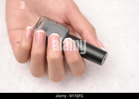 Female beautiful hands to hold a bottle of lacquer. Gel-lacquer. Stock Photo