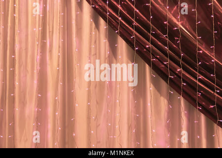 Beautiful festively decorated with lights curtains close-up as background. Stock Photo