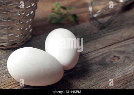 Goose eggs on wooden table with a basket and a whip Stock Photo