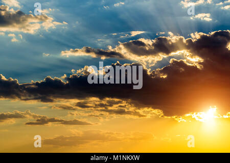 The sun hid behind black clouds and its rays beat up. Stock Photo